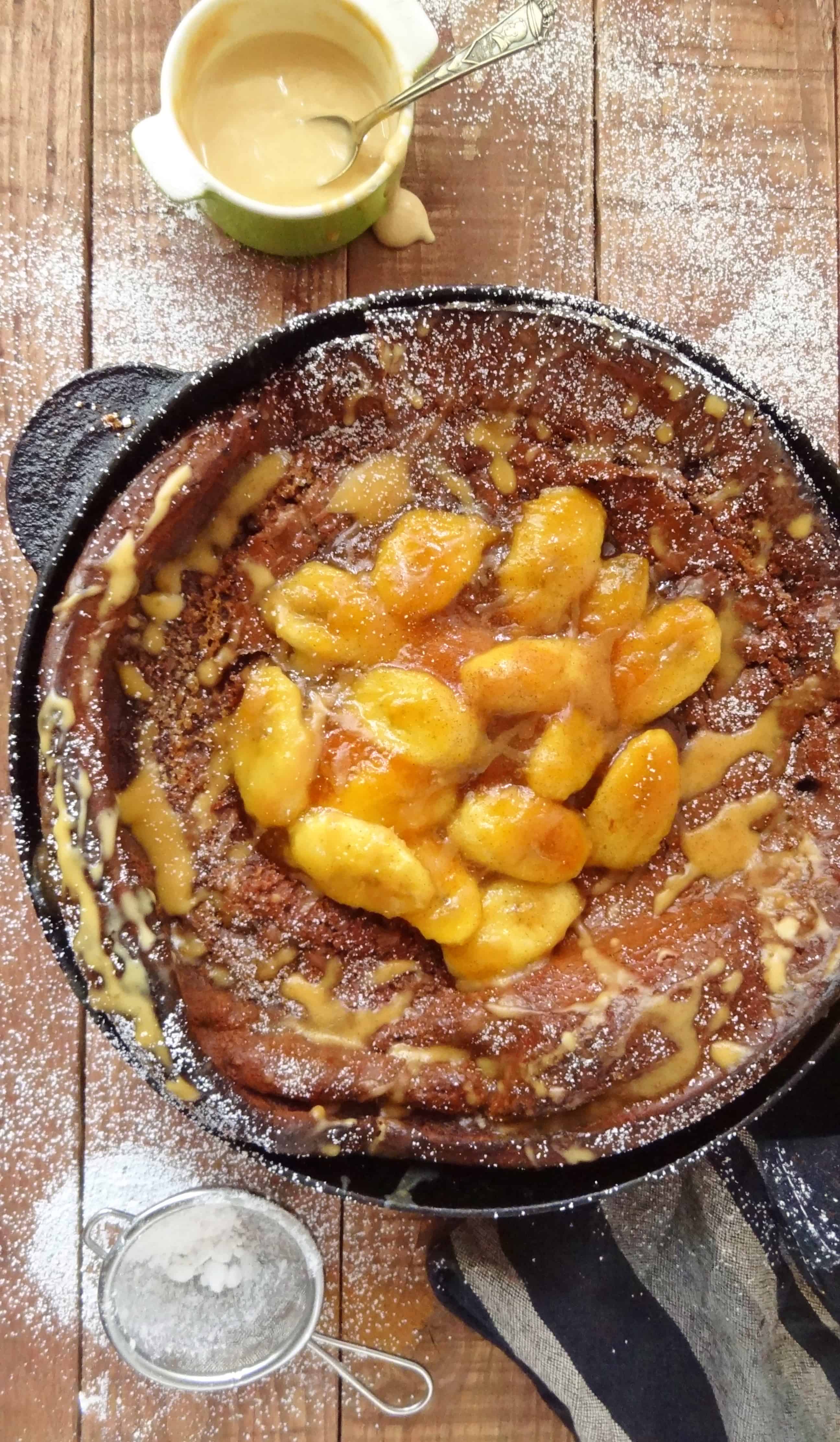 spiced chocolate dutch baby pancake with caramelised bananas and peanut butter drizzle