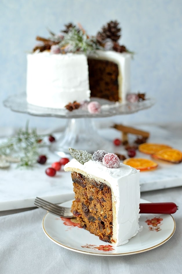Moist ginger fruitcake topped with marzipan, royal icing, sugared cranberries, rosemary and bay leaves, dried orange slices, pine cones and whole spices - Domestic Gothess