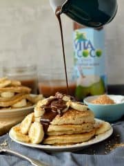 Toasted coconut pancakes with chocolate fudge sauce and banana, a decadent breakfast or brunch.