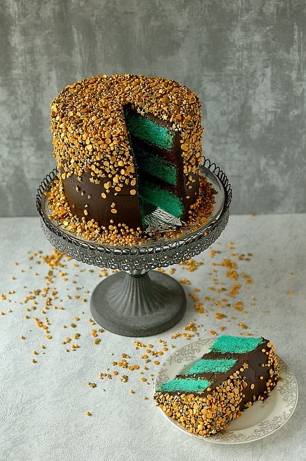 Layers of velvety vanilla cake with fudgy chocolate buttercream and a cascade of gold sprinkles