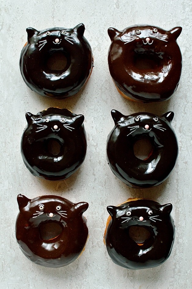 Chocolate glazed fried yeasted ring doughnuts with a cute black cat design, perfect for Halloween!