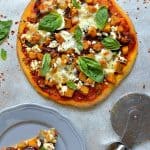 Pumpkin pizza dough topped with roast pumpkin and red onion, tomato sauce, mozzarella, rosemary, goats cheese and basil