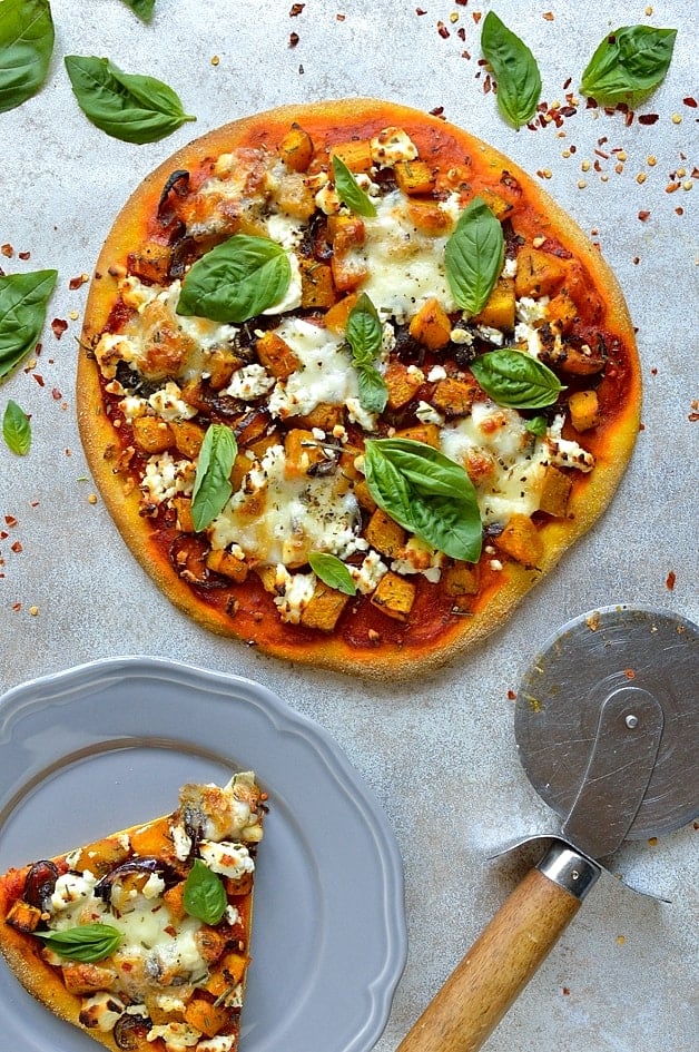 Pumpkin pizza dough topped with roast pumpkin and red onion, tomato sauce, mozzarella, rosemary, goats cheese and basil