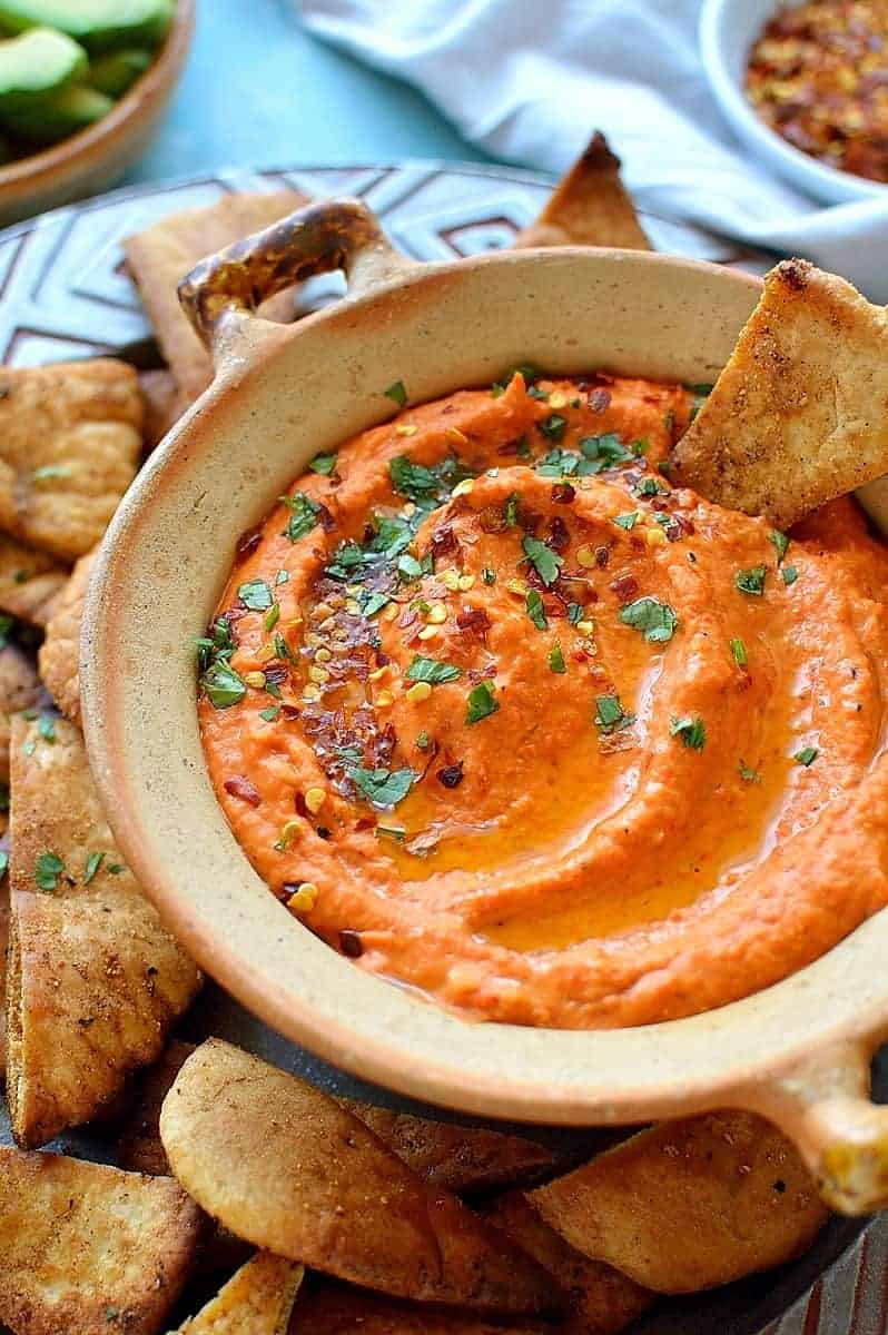 Roasted red pepper and chilli hummus with home-made seasoned pitta chips. Easy to make and the perfect snack!