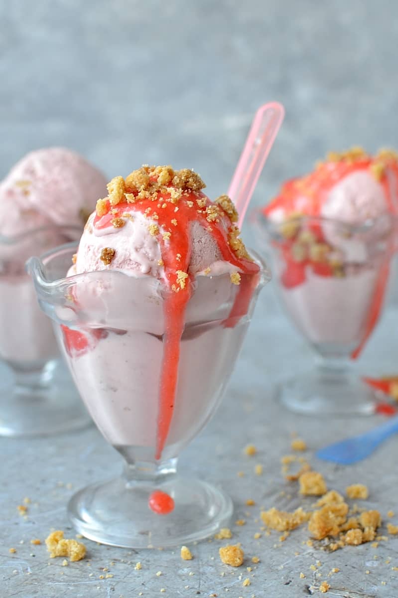 Roasted rhubarb and strawberry crumble ice cream - a delicious fruity ice cream filled with chunks of buttery crumble and topped with a tangy rhubarb strawberry sauce.