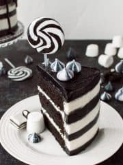 A slice of black and whitestriped monochrome chocolate and vanilla cake topped with a lollipop.