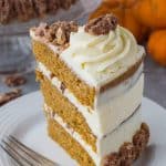 Close-up shot of a slice of pumpkin spice layer cake with mascarpone cream and sugared pecans.