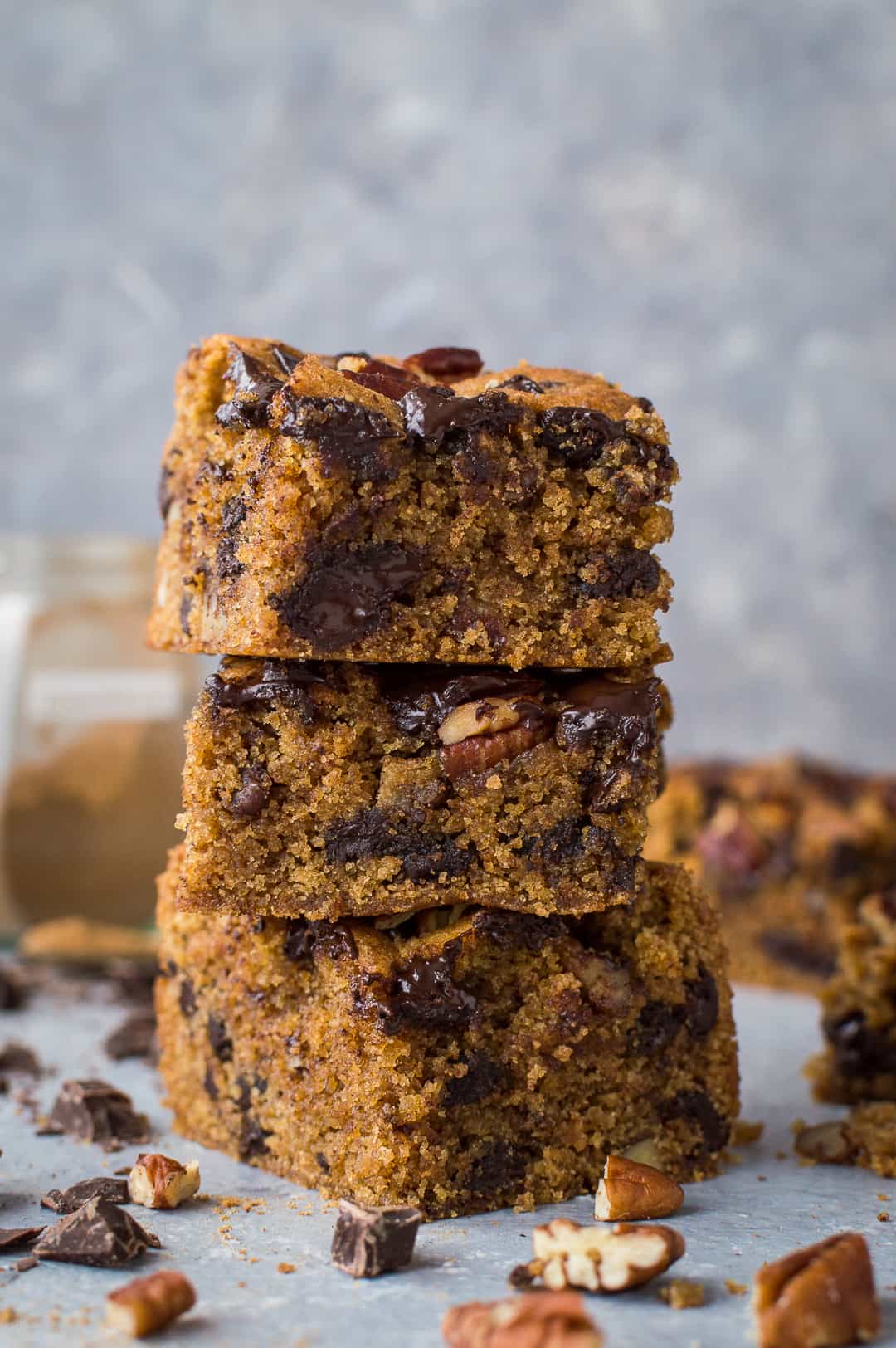 A stack of egg and dairy free vegan peanut butter chocolate chip pecan bars on a grey background
