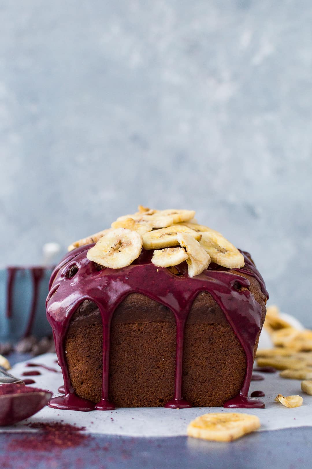 Vegan chocolate chip banana bread topped with a blueberry glaze and banana chips.