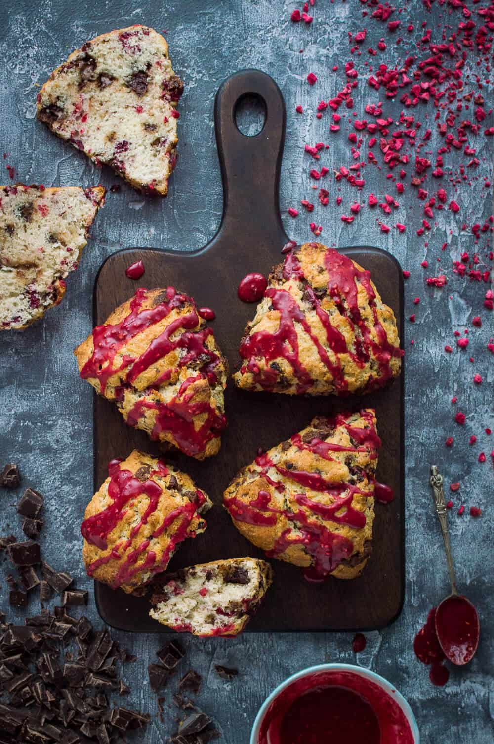 vegan chocolate raspberry scones with raspberry glaze on a wooden board.