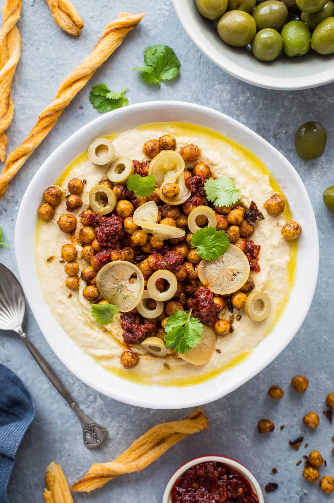 Hummus topped with crispy Ras el hanout roasted chickpeas, preserved lemon, olives and olive oil