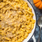 Close up of a pan of vegan pumpkin mac and cheese on a grey background.