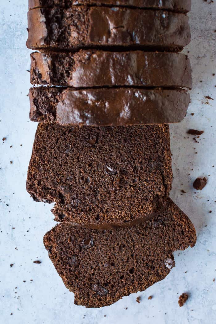 A loaf of sliced vegan double chocolate banana bread on a grey background.