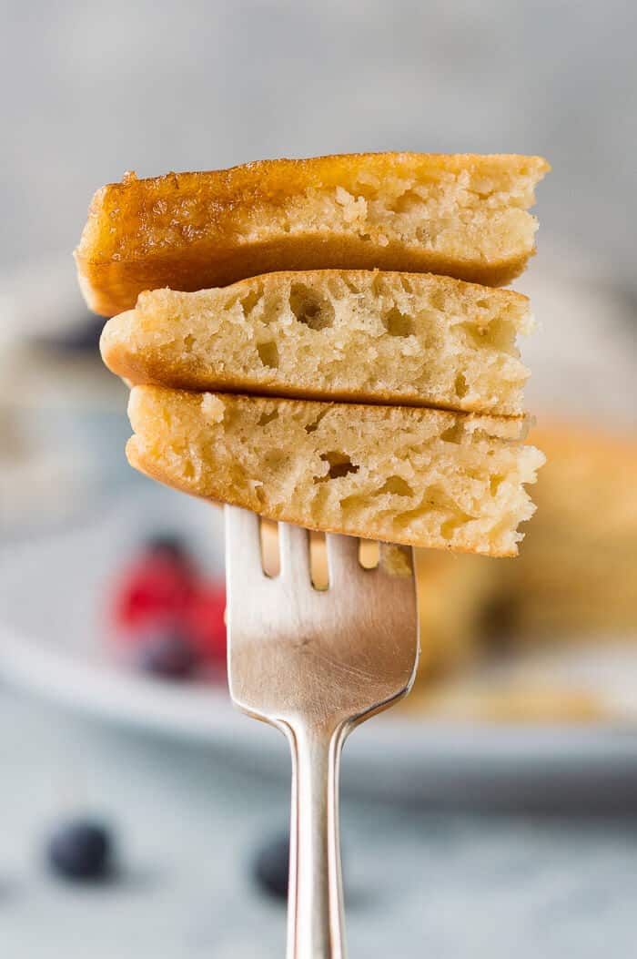 Close up of a fork holding sliced fluffy vegan vanilla pancakes.