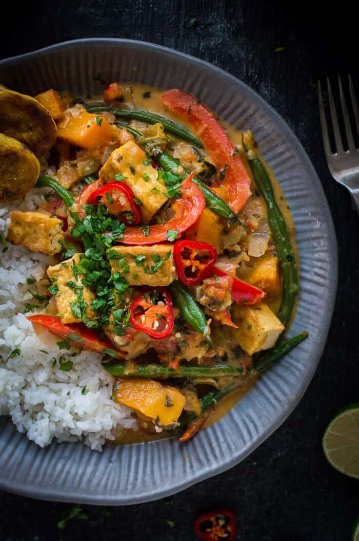Close up of a grey bowlful of vegan tofu moqueca with white rice and fried plantain.