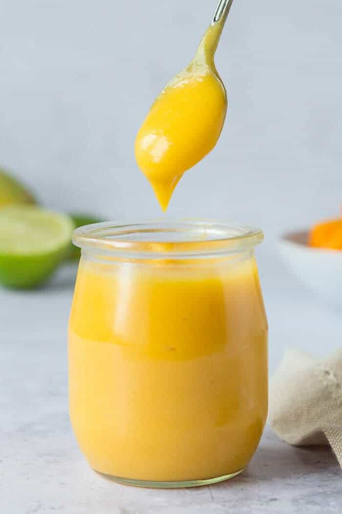 a small jar of vegan mango curd with a spoonful being taken out.