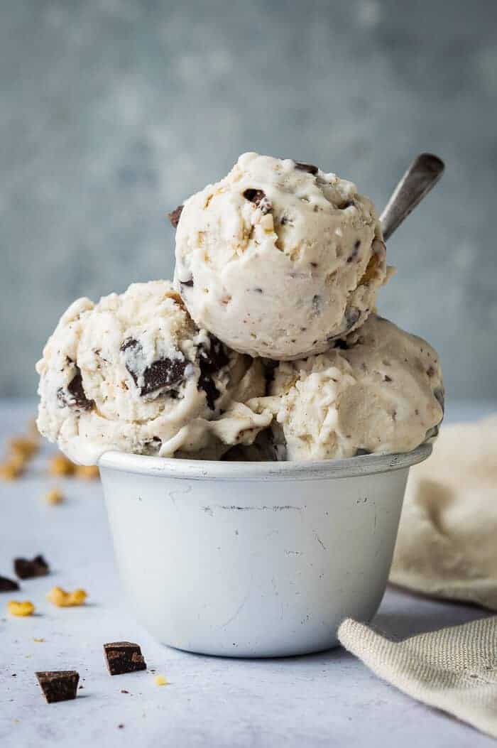 Three scoops of vegan banana ice cream with chocolate and walnuts in a metal dish.
