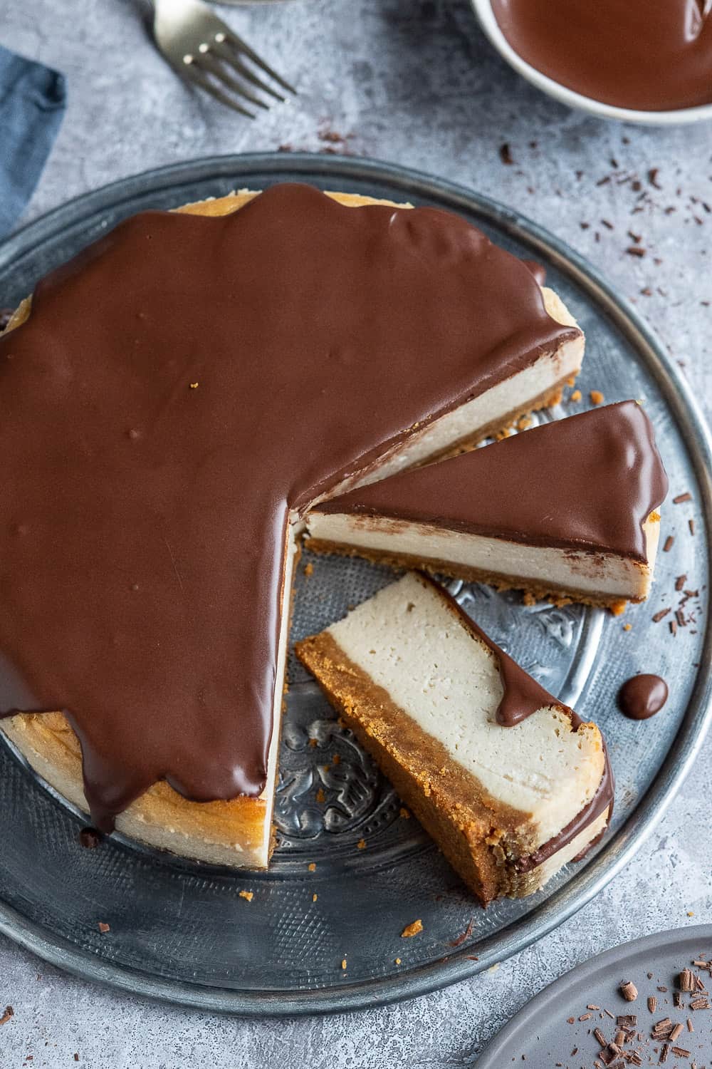 vegan cheesecake on a metal platter with two slices, one on it's side.