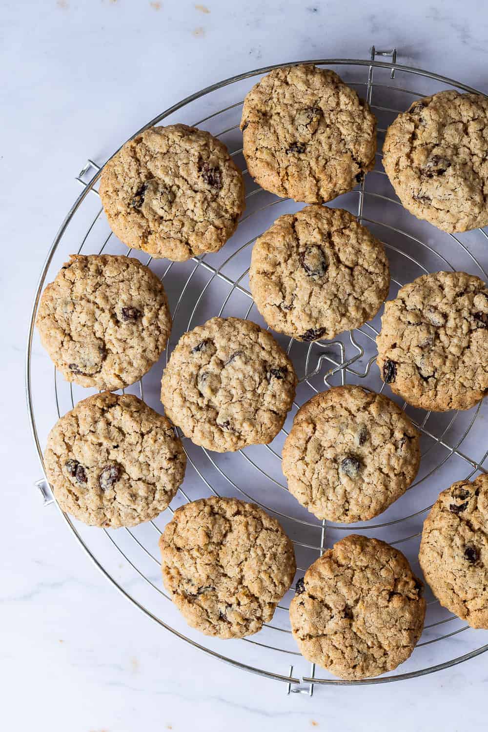 Vegan oatmeal raisin cookies on a round wire rack on a marble background.