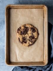 One giant cookie on a baking sheet on a grey background.