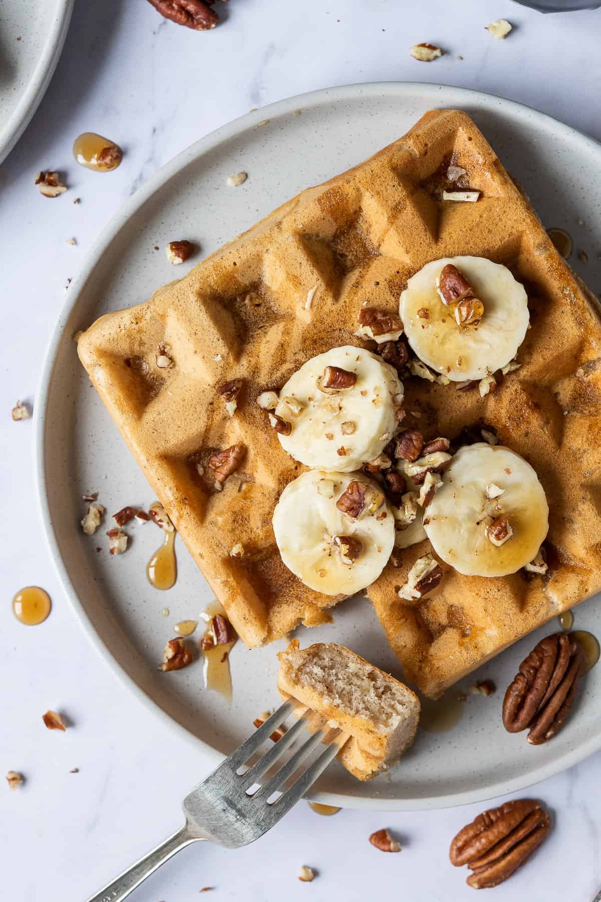 Close up of a vegan banana waffle with a forkful removed.