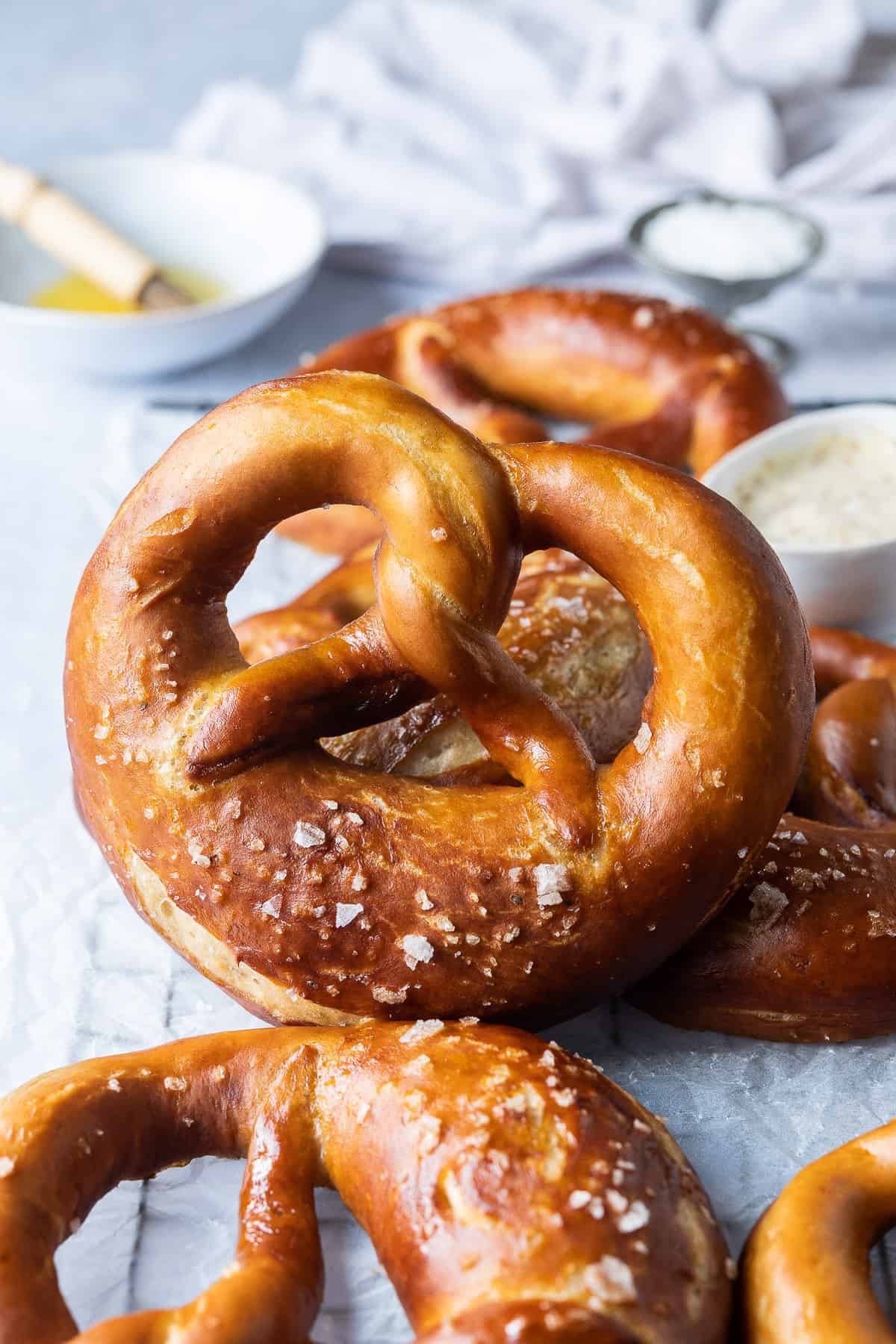 Close up of a vegan beer pretzel on a wire rack with a bowl of melted butter and a brush.