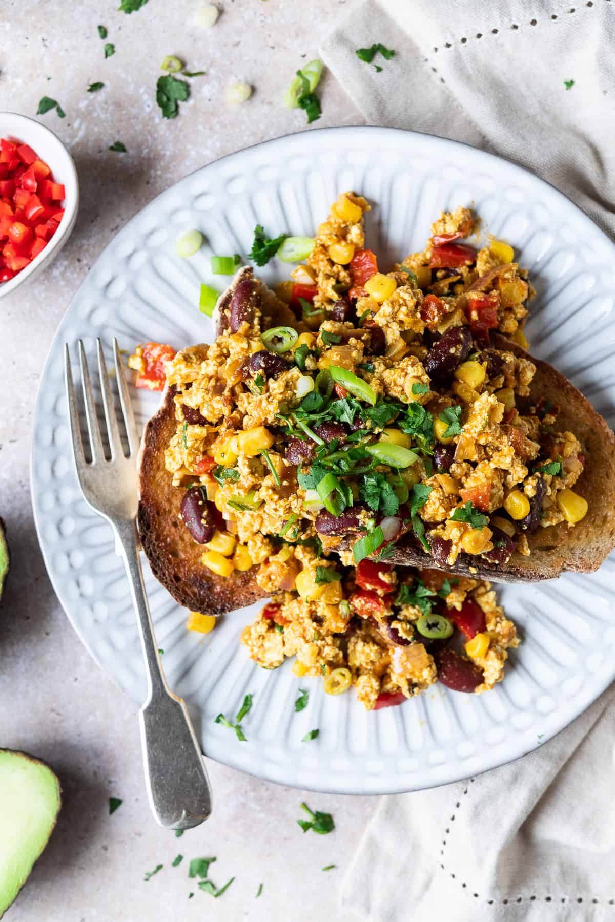 Mexican style tofu scramble on top of toast on a white plate.