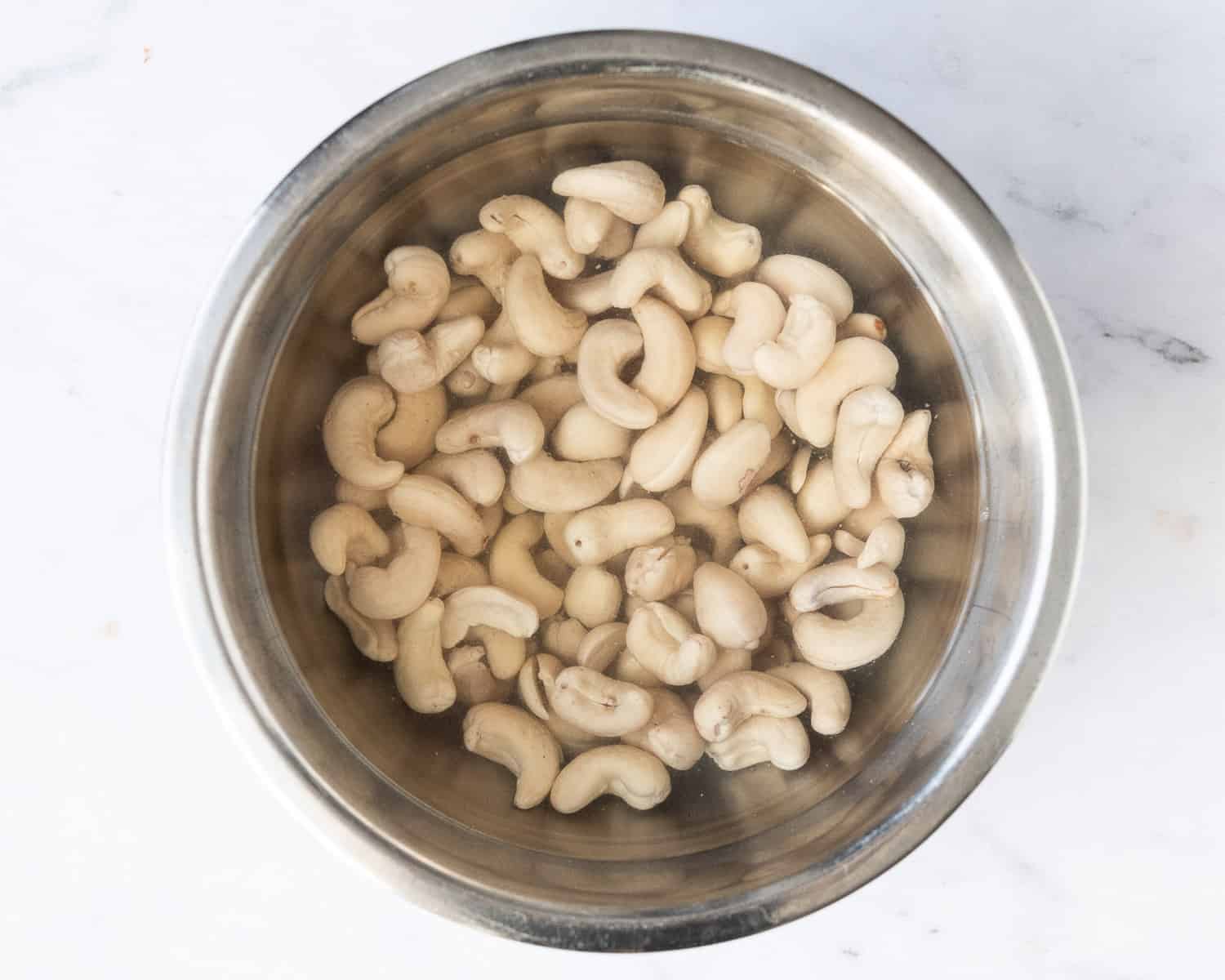 Step 1 - the cashews soaking in a metal bowl.