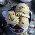 Close up of scoops of vegan pistachio ice cream in an enamel mug.