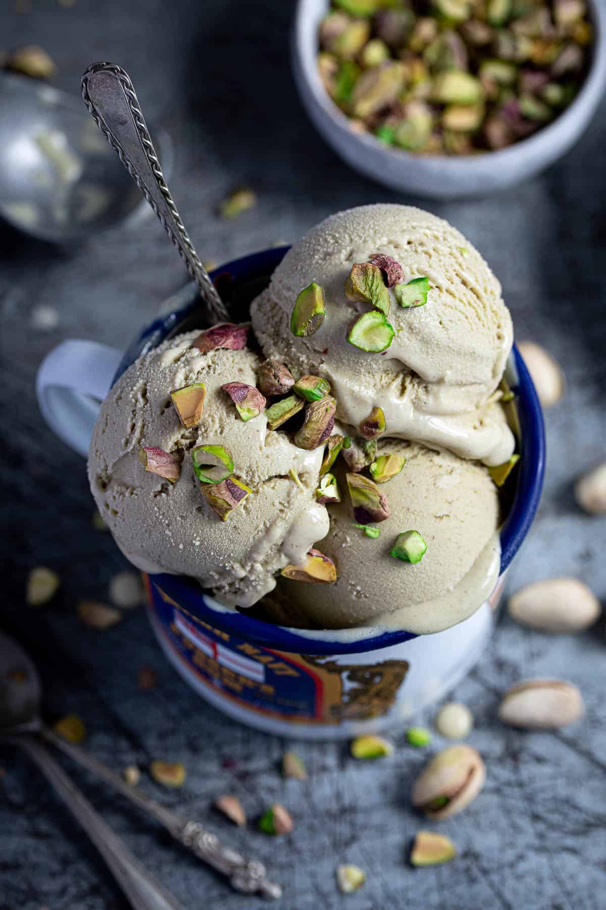 Close up of scoops of vegan pistachio ice cream in an enamel mug.