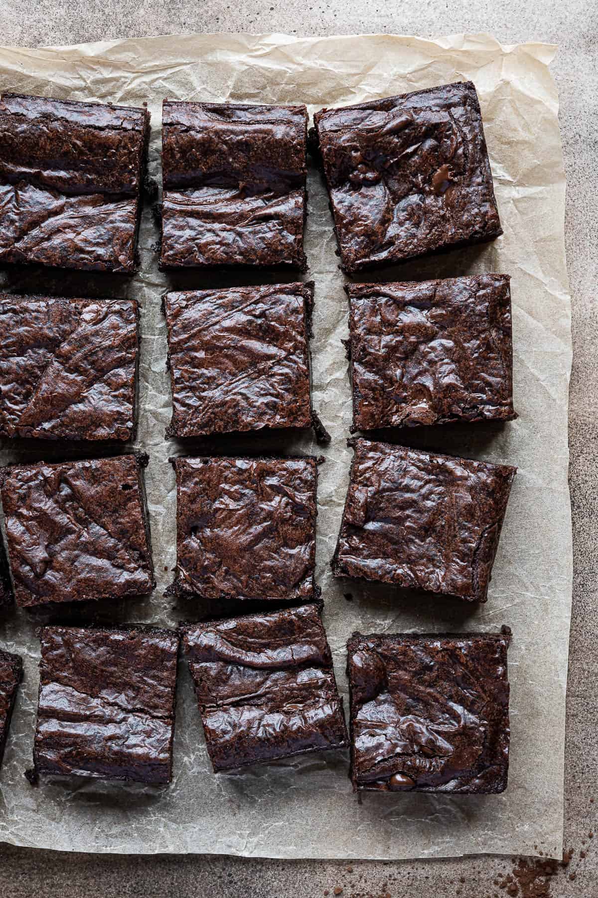 Fudgy vegan brownies on a sheet of baking parchment.