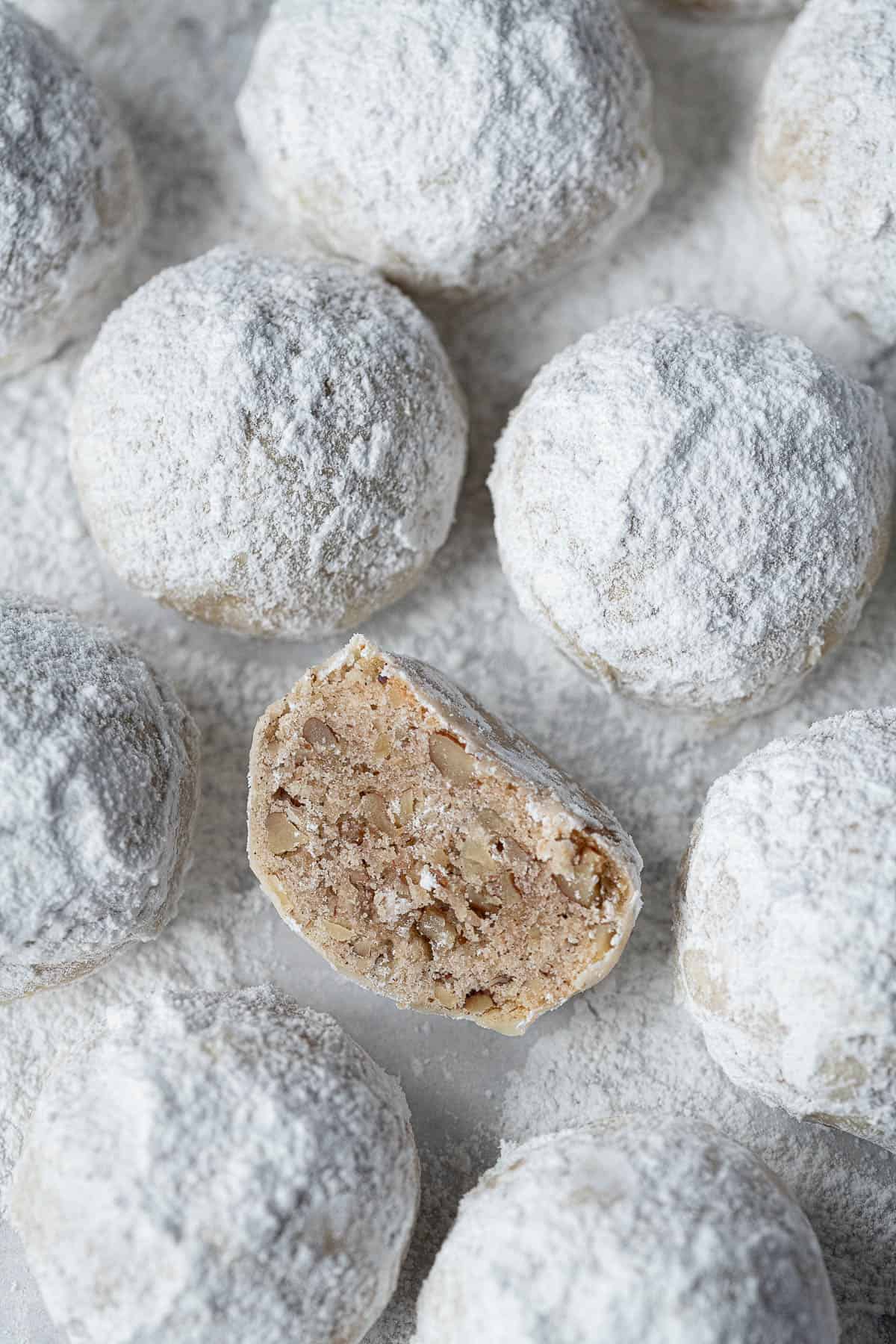 Close up of a vegan pecan snowball cookie that has been sliced in half.