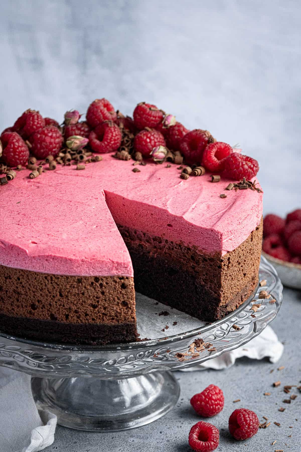 Close up of the sliced vegan chocolate raspberry mousse cake on a glass cake stand.