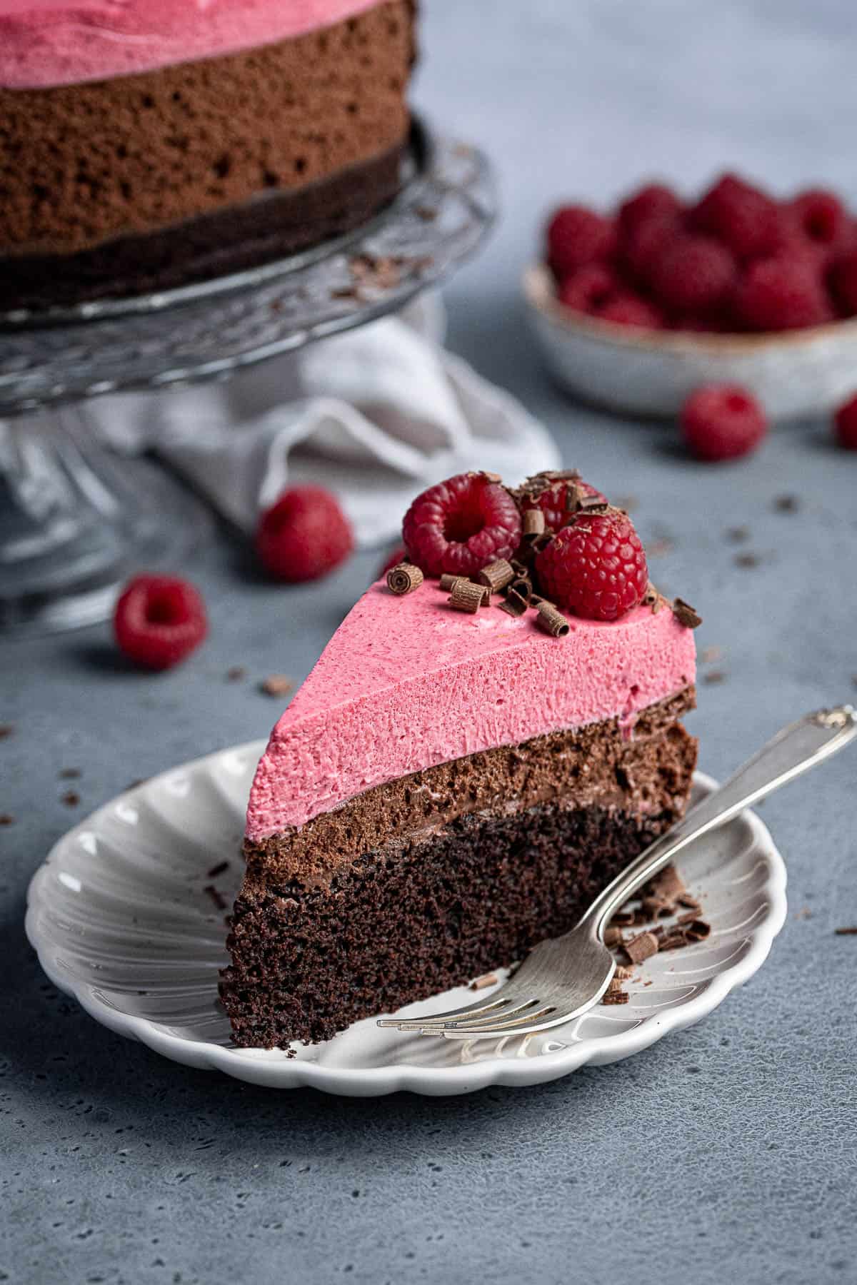 A slice of vegan chocolate raspberry mousse cake on a plate.