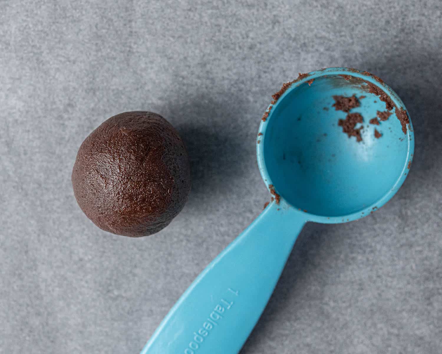 A ball of cookie dough with a tablespoon measure.