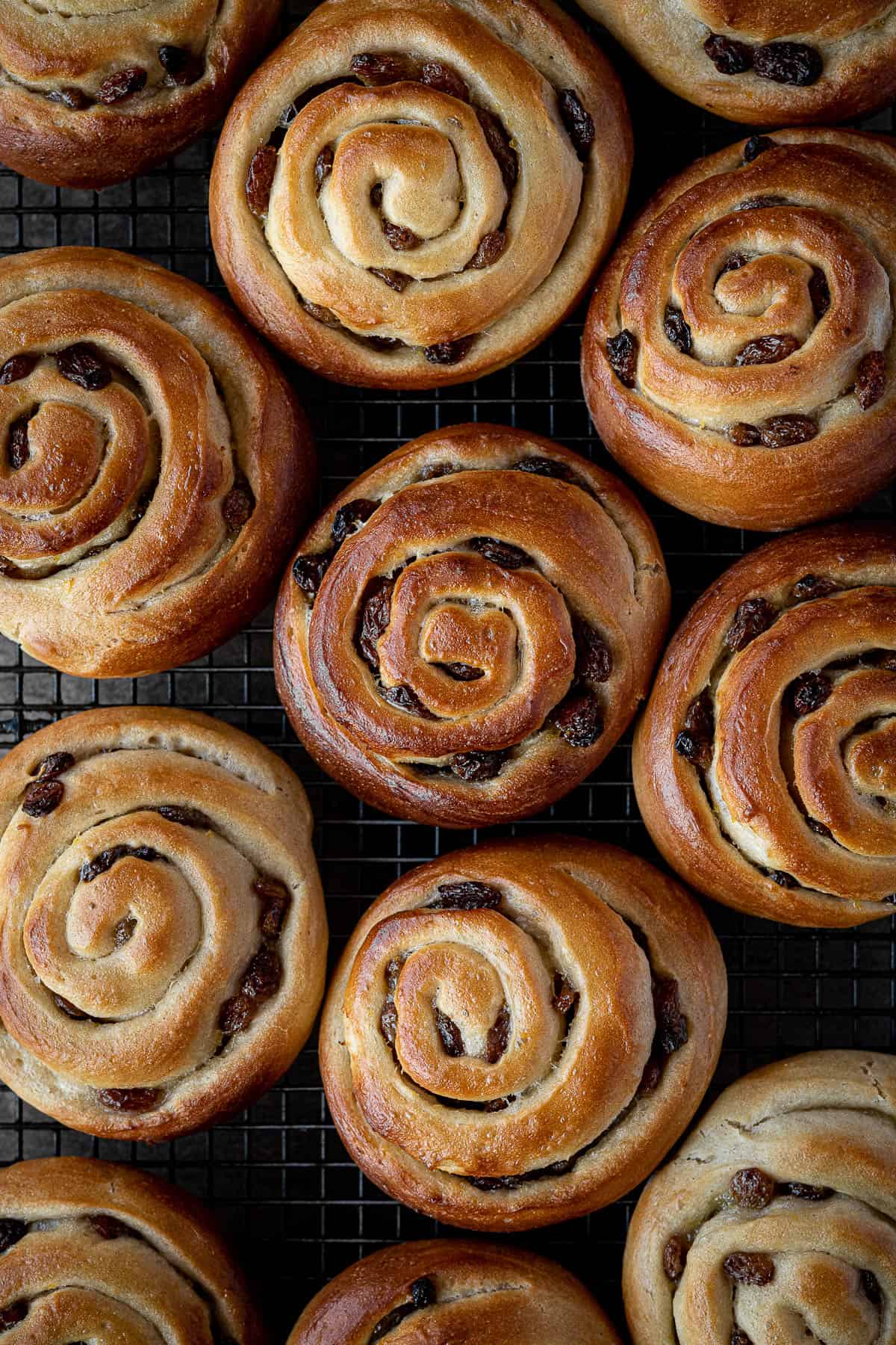 Un-iced Belgian buns on a wire rack.