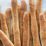 Close up of breadsticks on baking parchment.