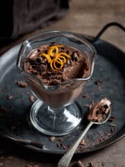 Vegan chocolate orange pot on a metal tray with a spoonful removed.