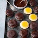 Vegan jaffa cakes on a metal tray with a bowl of chocolate.