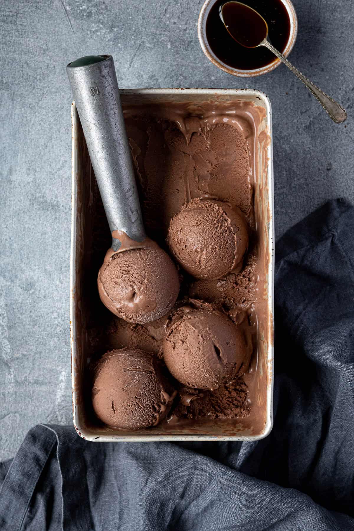 Veggan malted chocolate ice cream in a loaf tin with a bowl of malt extract.