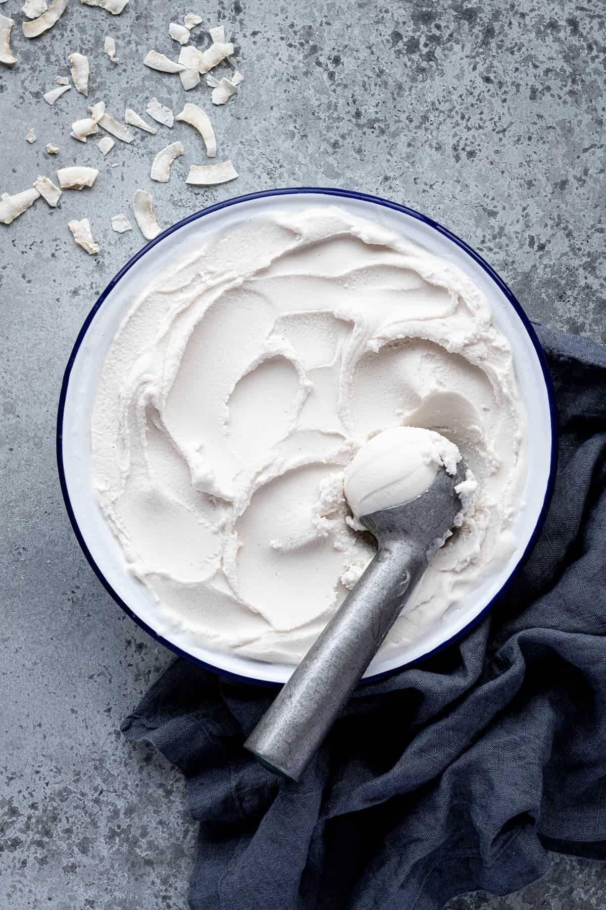 A round dish of easy coconut ice cream with an ice cream scoop.