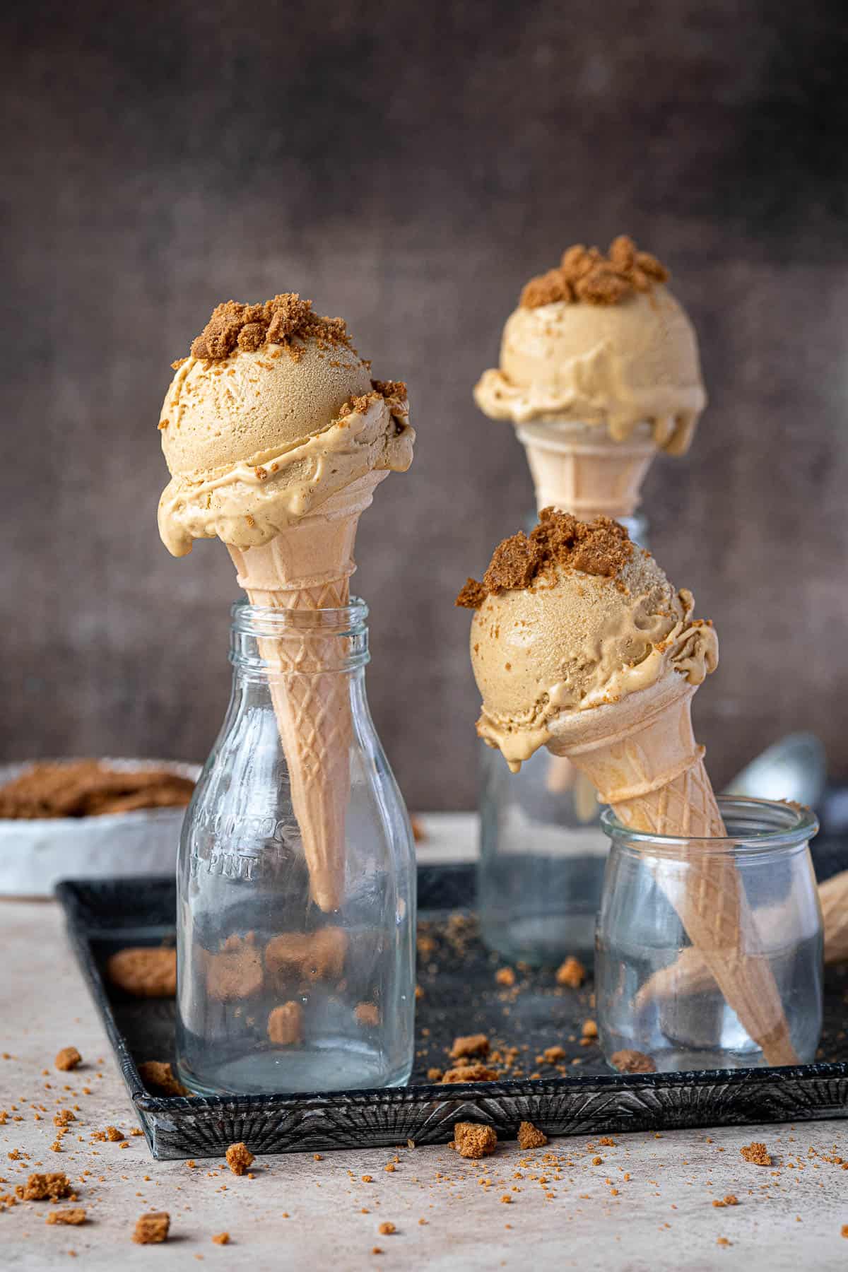 Three cones of vegan pumpkin ice cream topped with crushed cookies.
