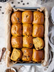 Chocolate chip pumpkin rolls in a tin with bowls of chocolate chips and pumpkin spice.