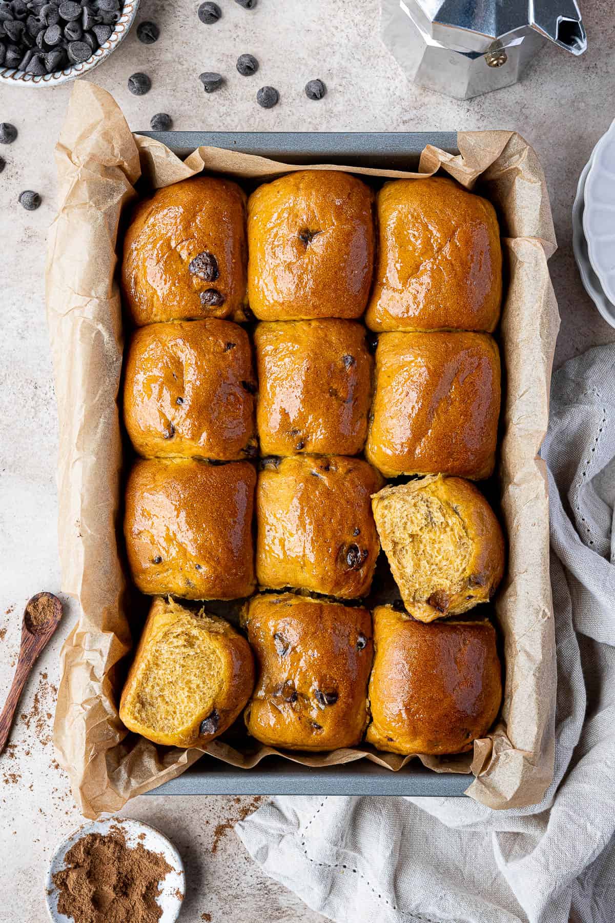 Chocolate chip pumpkin rolls in a tin with bowls of chocolate chips and pumpkin spice.