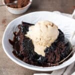 A slice of self-saucing chocolate pudding in a bowl with a scoop of ice cream.