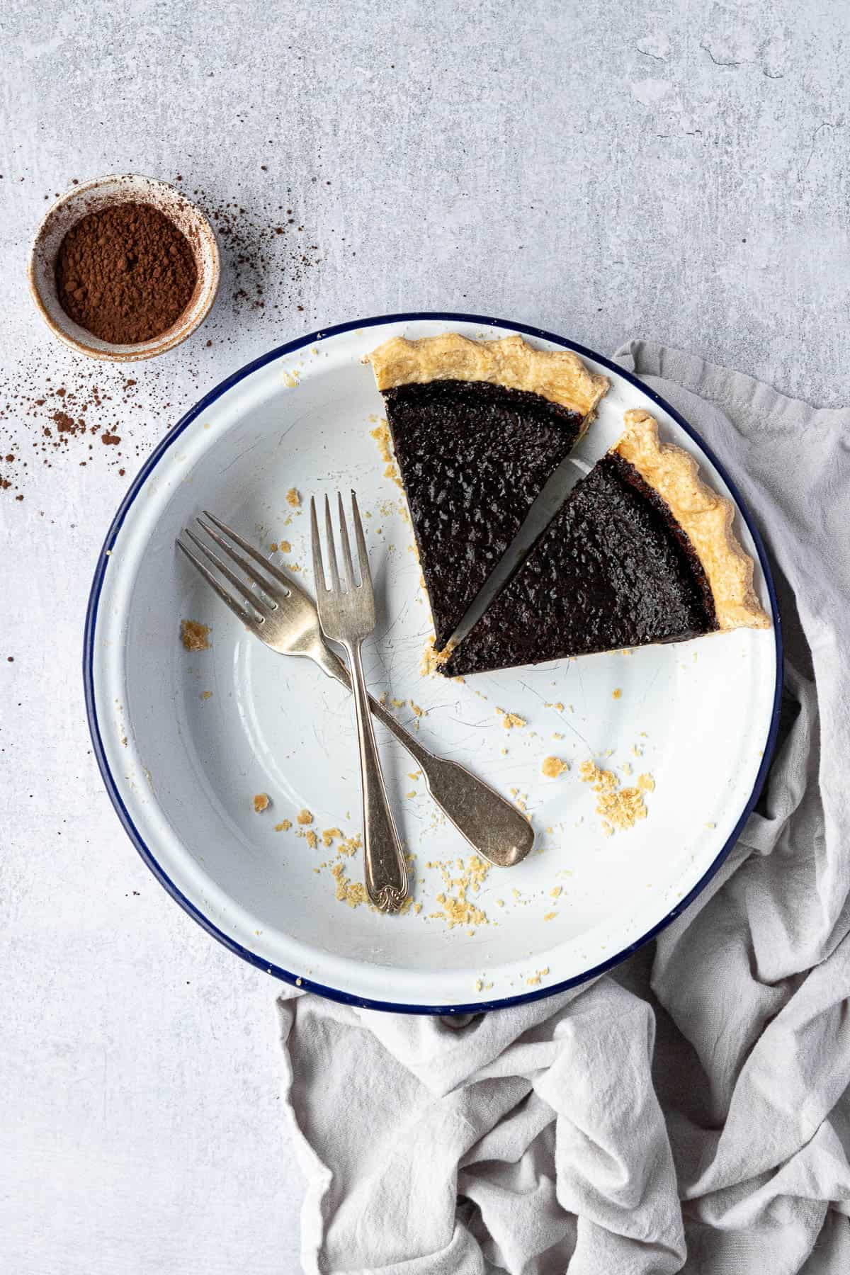 Two slices of vegan chocolate chess pie in a white pie dish with two forks.