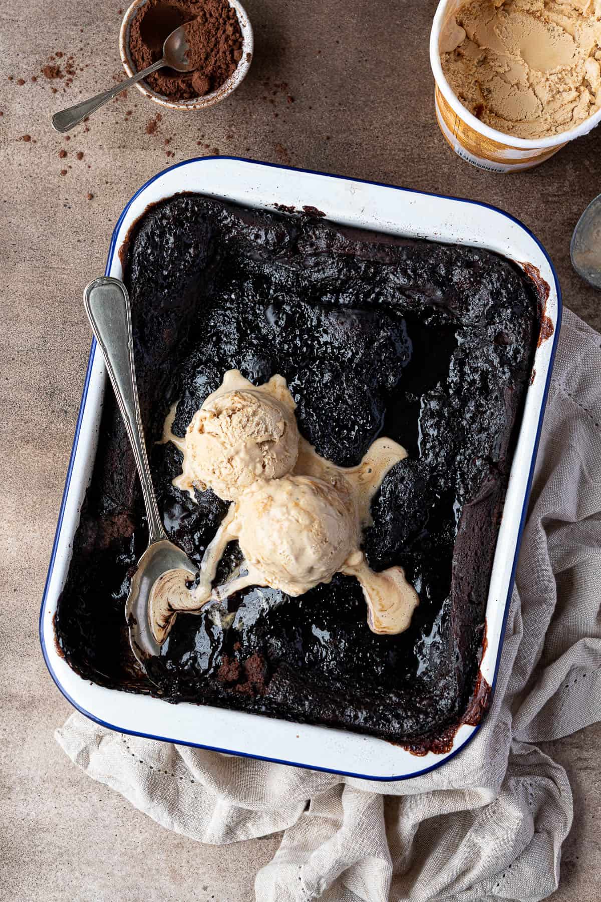 Vegan self-saucing chocolate pudding in a baking dish topped with ice cream.
