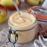 Vegan apple curd in a glass jar with apples and twine.