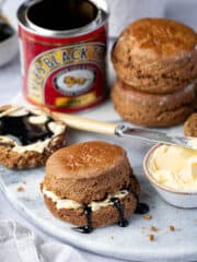 Vegan treacle scones on a marble board with a tin of treacle and a bowl of butter.