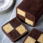 Chocolate orange Battenberg cake on a marble board with two slices cut.